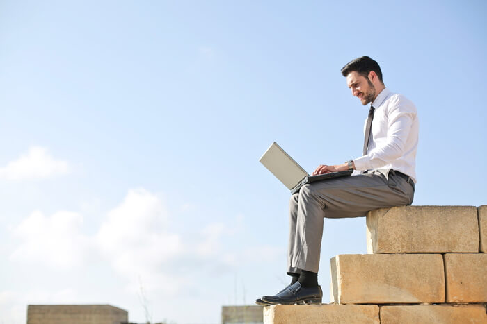 man sitting outside on bricks with laptop